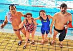 Piscina cubierta con cuatro nadadores posando junto al borde