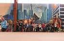 Mural de superhéroes en el colegio de Paradai con un grupo de personas