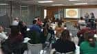 Interior de sala de conferencias con asistentes y pantalla de proyección