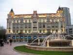 Fachada iluminada del edificio Casa Conde (Banco Herrero) y la fuente de la plaza al anochecer