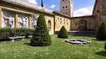 Vista del jardín interior con césped, setos y el muro histórico con relieves escultóricos