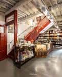 Vista interior del Almacén Concept Store con escaleras rojas y vigas de madera