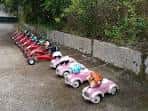 Fila de coches de pedales rojos y rosas, indicando una zona de actividades infantiles en el parque