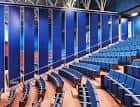 Interior de un auditorio o sala de conferencias con butacas azules y paneles divisorios
