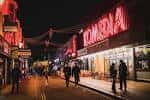 Vista nocturna de la calle y la entrada de Komedia Brighton con gente caminando