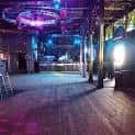 Vista interior de la sala de eventos vacía con pista de baile y barra iluminada