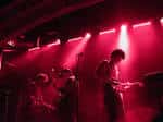 Interior del local de eventos con banda tocando en el escenario bajo intensa iluminación roja