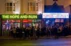 Vista exterior nocturna de The Hope and Ruin con gente en la entrada