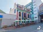 Área de asientos exterior del pub The Prince Albert con sombrillas verdes