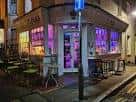 Fachada exterior del Artista Cafe & Gallery en esquina, iluminada de noche