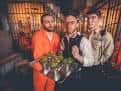 Tres actores o personal de Alcotraz posando con un servicio de cócteles en el bar temático