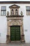 Detalle del portal principal del Antiguo Hospital de San Roque con puerta verde y esculturas superiores