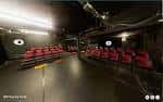 Interior del teatro de caja negra con asientos rojos y configuración de escenario