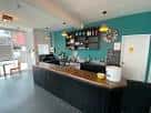 Área de bar y recepción del teatro con mostrador y pared turquesa