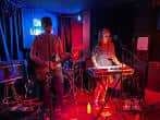 Actuación de música en directo en el escenario del local, iluminado con luces rojas y azules