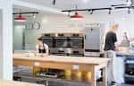 Interior del espacio de taller de panadería con hornos industriales y mesa central de trabajo