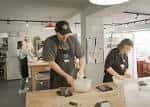 Participantes amasando en el taller de panadería con mesas de madera