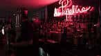 Zona de la barra con botellas y un letrero de neón rojo brillante
