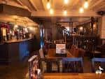 Interior del pub con mesas de madera, iluminación ambiental y zona de bar
