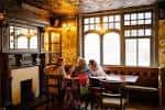 Interior acogedor del pub con chimenea y asientos junto a la ventana