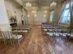 Interior de una sala de ceremonias con sillas doradas y suelo de parqué