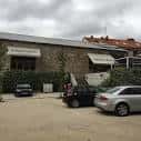 Exterior del edificio de piedra con toldos y zona de aparcamiento