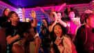 Grupo de personas disfrutando y cantando en una sala de karaoke con luces de fiesta