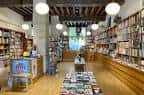 Pasillo principal de la Librería Gil con techo de vigas de madera y estanterías a ambos lados.