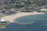 Vista aérea panorámica de la Playa de El Arbeyal, el espigón y la zona urbana de Gijón
