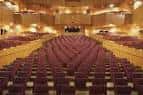 Interior del auditorio principal con filas de butacas rojas y pasillos centrales
