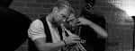 Músico tocando la trompeta en blanco y negro durante una actuación de jazz en el club