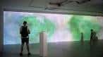 Interior de la galería de arte con una gran proyección digital abstracta y visitantes