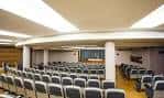 Interior del salón de actos o auditorio con filas de asientos y podio