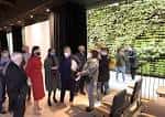 Interior de la sala de eventos con muro vegetal y asistentes durante una inauguración