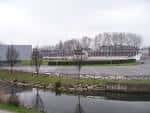 Vista general del Complejo Deportivo Las Mestas con edificios y canal en primer plano