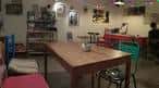 Zona de cafetería con mesa de madera y sillas de colores variados