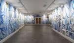 Espacio de galería con decoración mural abstracta en tonos azules y blancos.