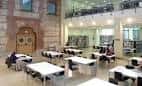 Zona de lectura interior con mesas y arquitectura que combina elementos antiguos y modernos