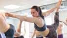 Primer plano de una mujer realizando la postura del bailarín (Natarajasana) durante una clase de yoga