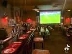 Interior del pub mostrando la barra y una pantalla de proyección para eventos