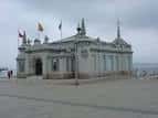 Perspectiva exterior del Palacete con banderas ondeando bajo cielo nublado
