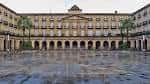 Vista frontal y simétrica de la fachada principal de la Plaza Nueva de Bilbao con el suelo mojado