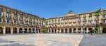 Amplia vista panorámica de la Plaza Nueva de Bilbao bajo un cielo azul despejado