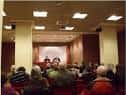 Interior de la sala de actos o conferencias con público y mesa presidencial
