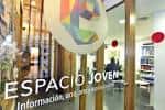 Entrada acristalada del Espacio Joven con señalización y vista parcial del interior
