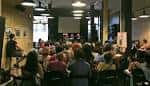 Vista amplia de la sala de eventos con el público y el escenario al fondo