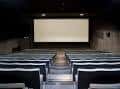 Vista frontal del interior de la sala de cine con la pantalla vacía y filas de butacas
