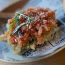 Tosta o tapa gourmet con tomate y anchoa servida sobre papel decorativo