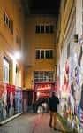 Vista nocturna del callejón de acceso a Dabadaba con murales y luces