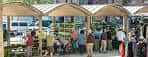 Puestos de mercado o evento bajo toldos en la Plaza Simón Bolívar, mostrando actividad
